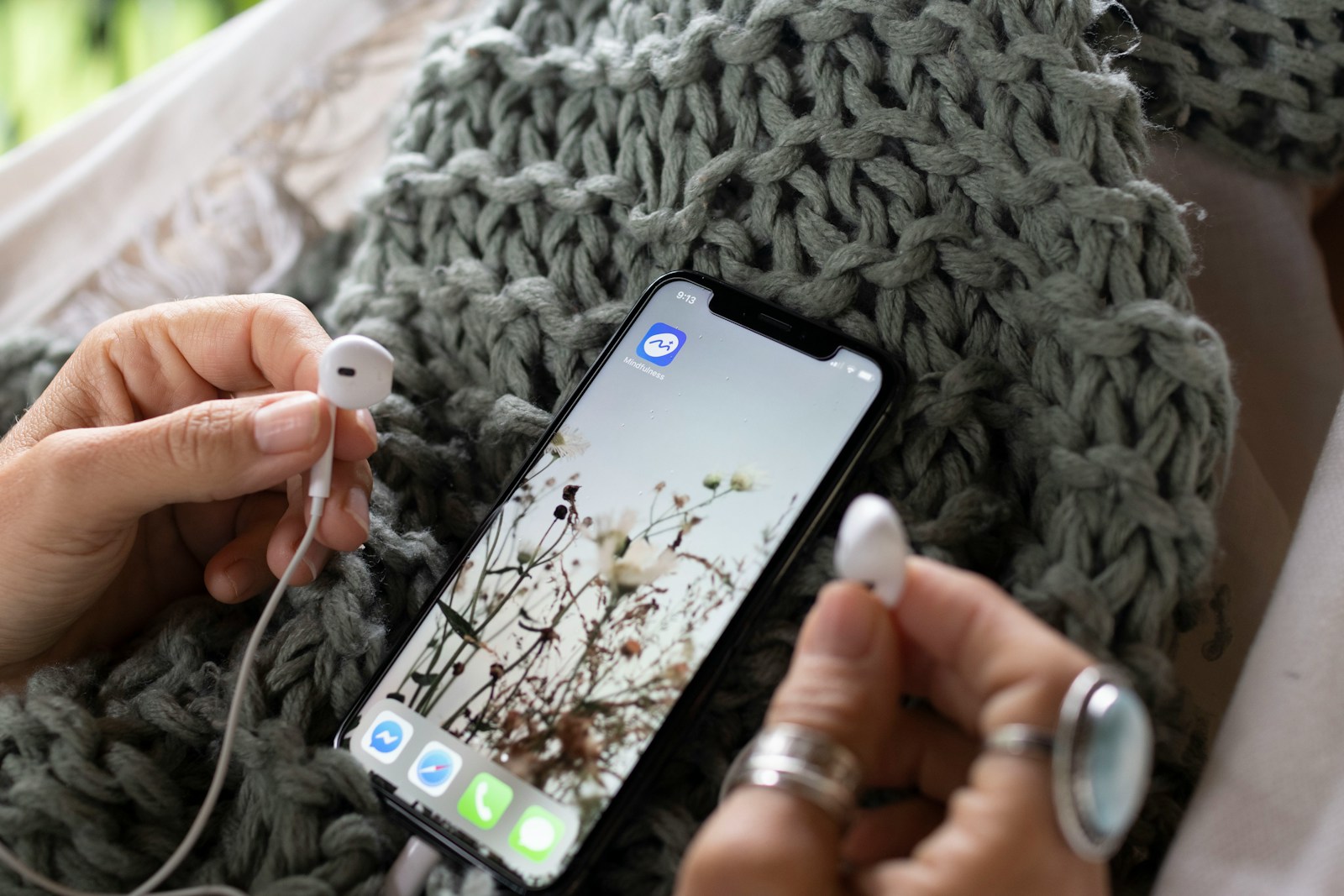 a person holding a cell phone and ear buds